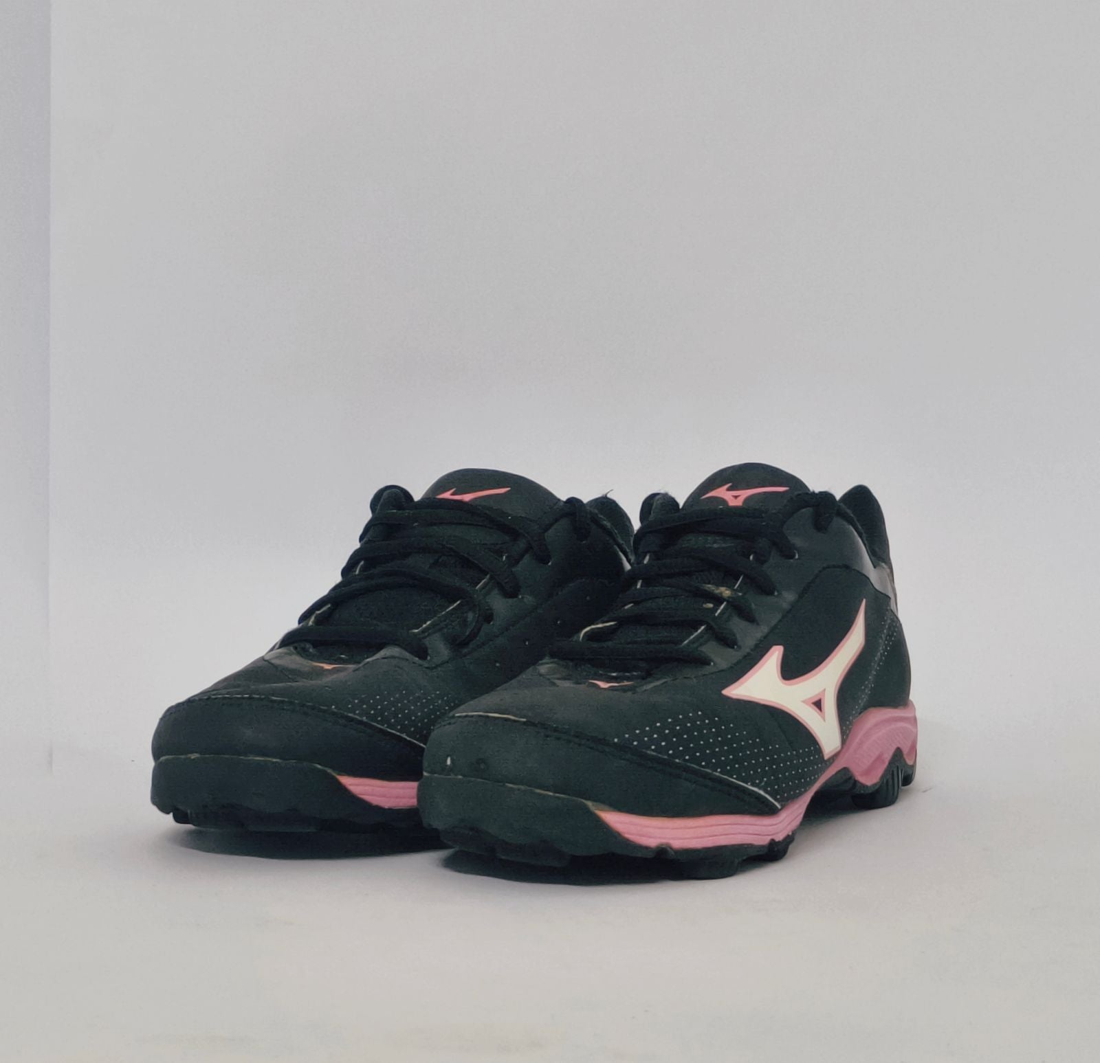 Mizuno Wave Lynx field hockey shoe in black with a pink logo and pink studded turf sole.