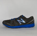 charcoal grey and black New Balance running shoe featuring royal blue laces, logo, and midsole.