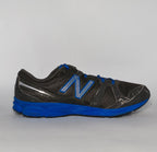 charcoal grey and black New Balance running shoe featuring royal blue laces, logo, and midsole.