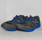 charcoal grey and black New Balance running shoe featuring royal blue laces, logo, and midsole.
