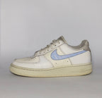 white Nike Air Force 1 Low sneaker featuring a light blue patterned Swoosh and a vintage sail-colored midsole.