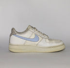 white Nike Air Force 1 Low sneaker featuring a light blue patterned Swoosh and a vintage sail-colored midsole.