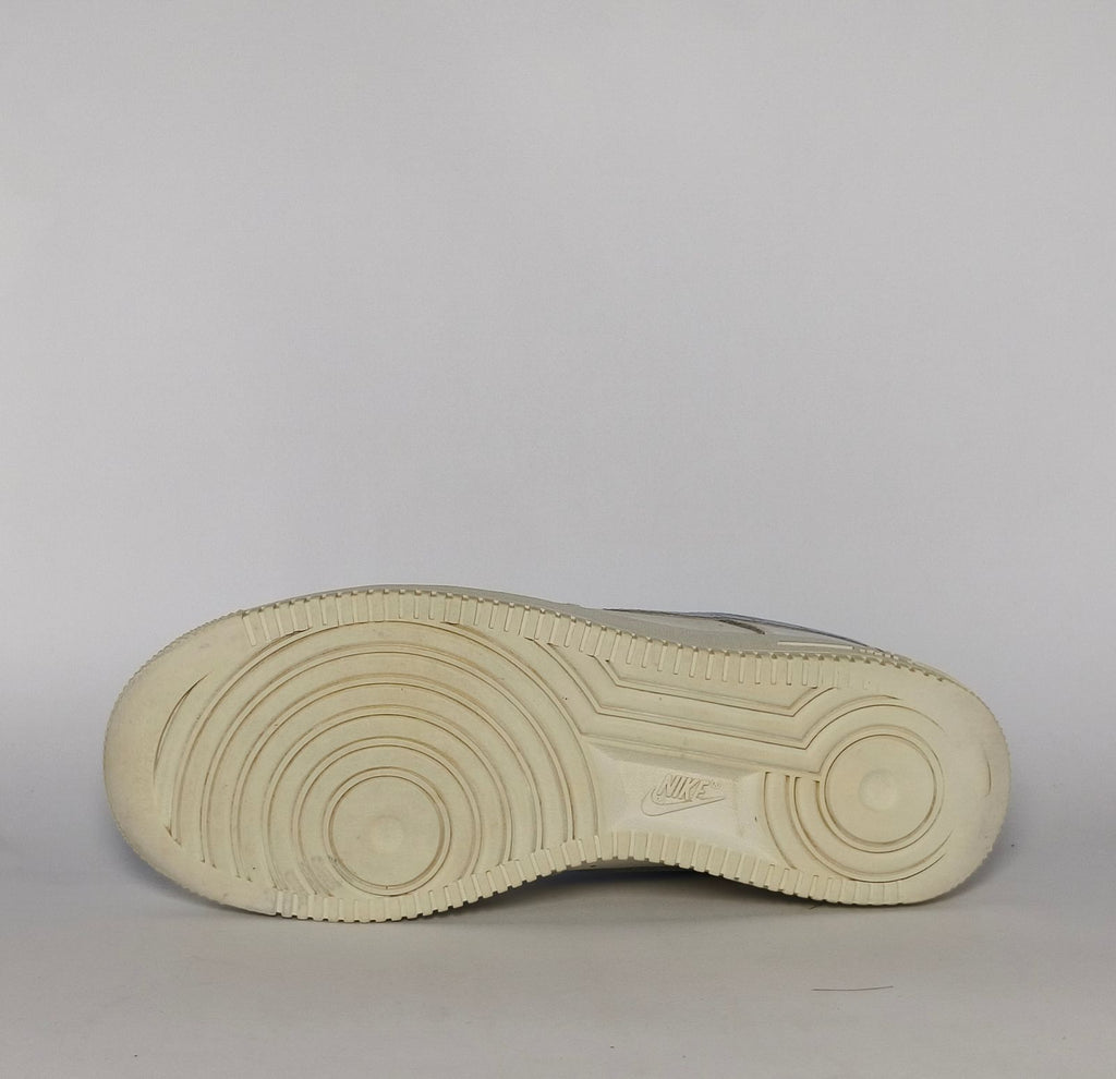 white Nike Air Force 1 Low sneaker featuring a light blue patterned Swoosh and a vintage sail-colored midsole.