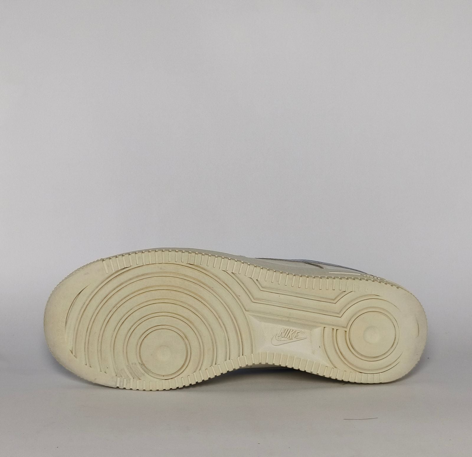 white Nike Air Force 1 Low sneaker featuring a light blue patterned Swoosh and a vintage sail-colored midsole.