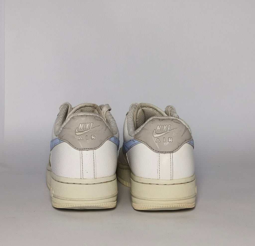 white Nike Air Force 1 Low sneaker featuring a light blue patterned Swoosh and a vintage sail-colored midsole.