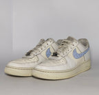 white Nike Air Force 1 Low sneaker featuring a light blue patterned Swoosh and a vintage sail-colored midsole.