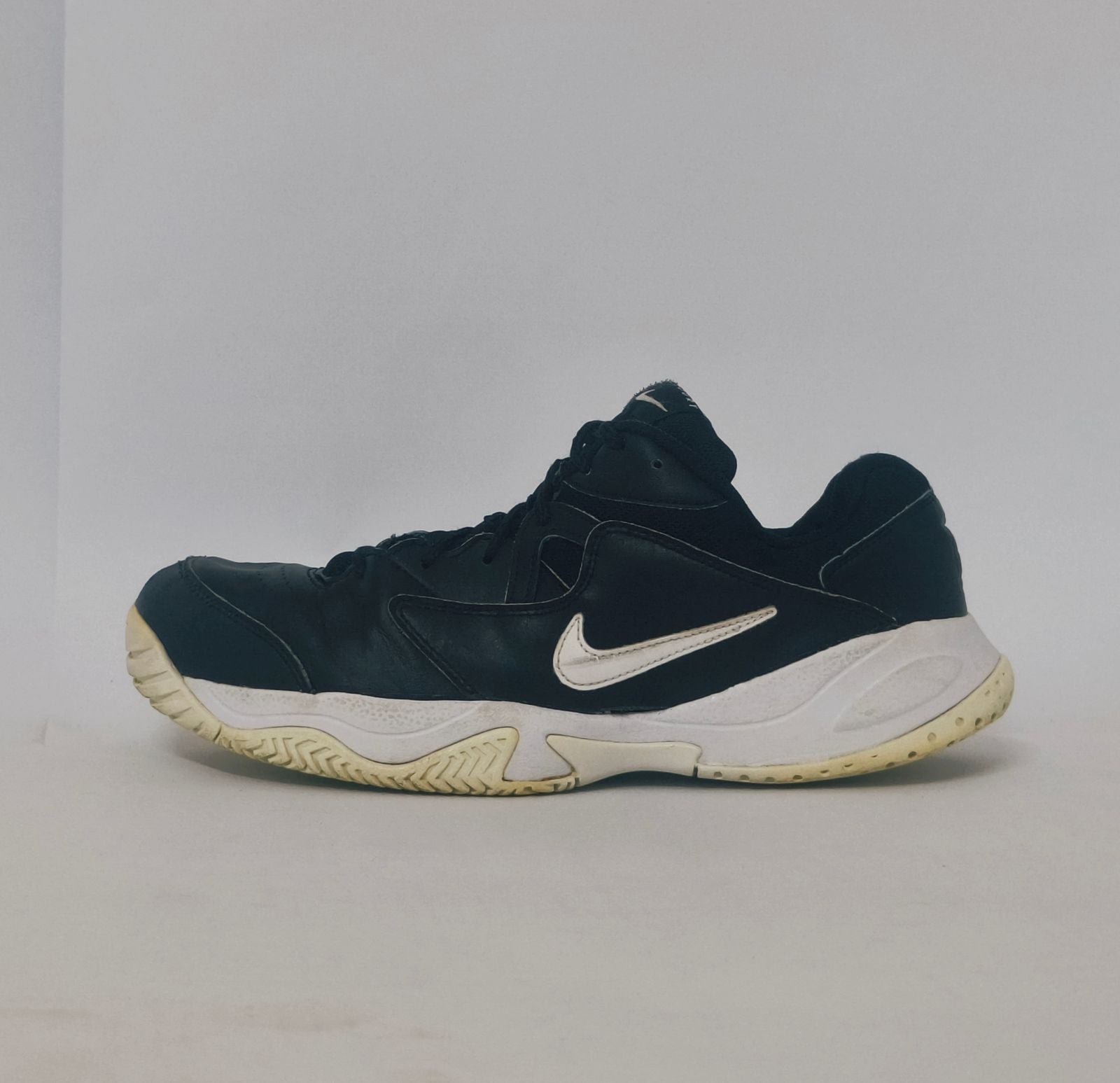 black Nike court sneaker featuring a white Swoosh and a thick white midsole with court-ready traction.