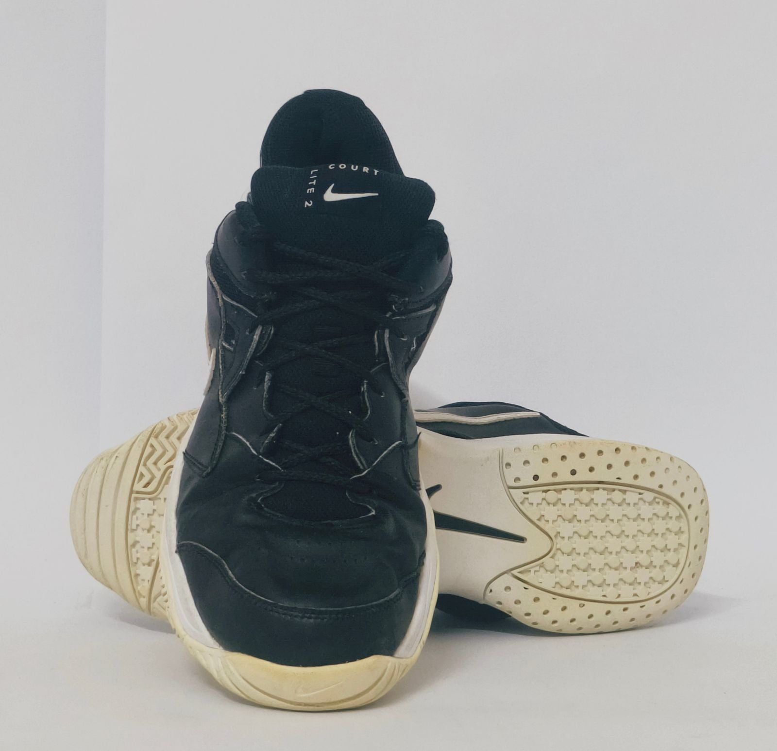 black Nike court sneaker featuring a white Swoosh and a thick white midsole with court-ready traction.