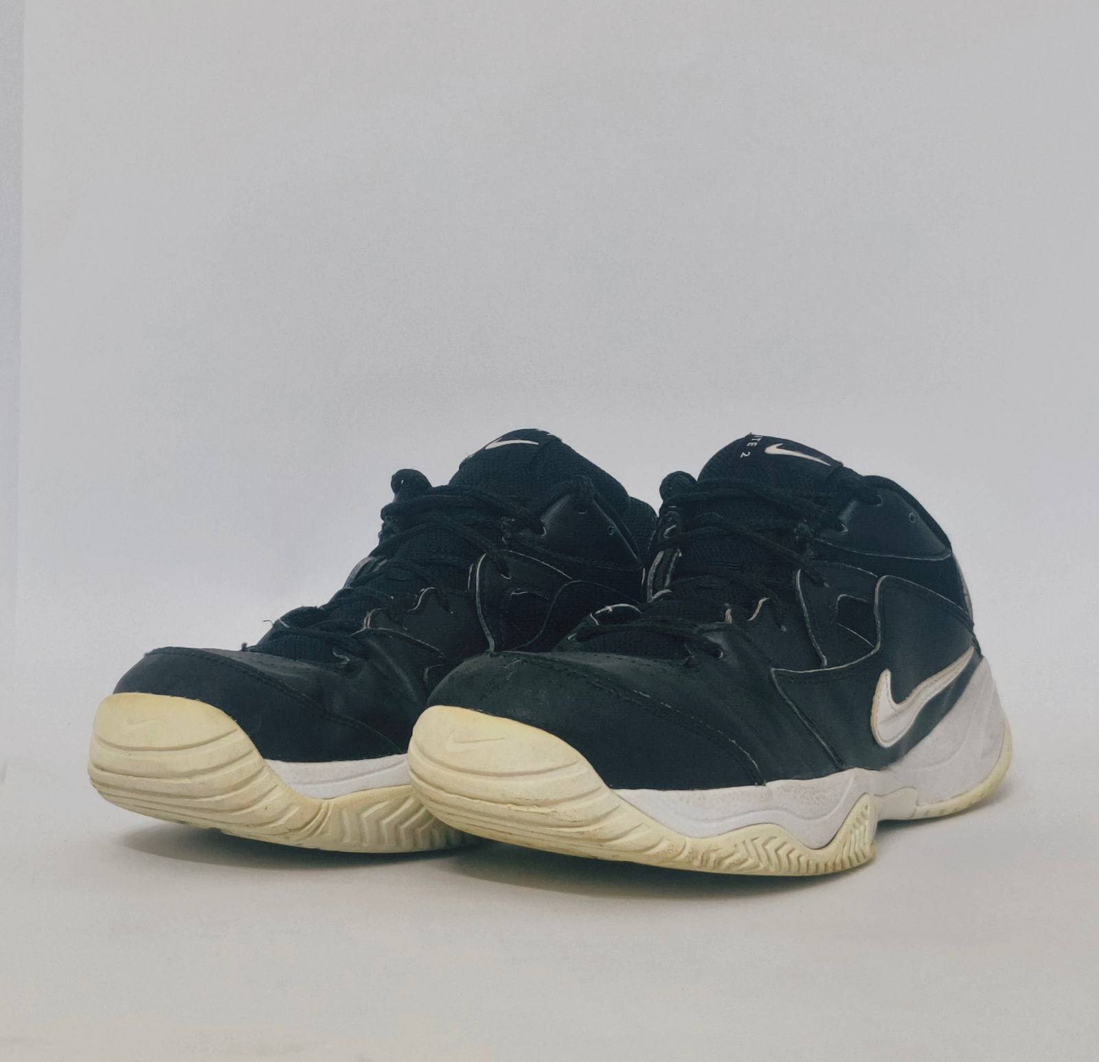 black Nike court sneaker featuring a white Swoosh and a thick white midsole with court-ready traction.