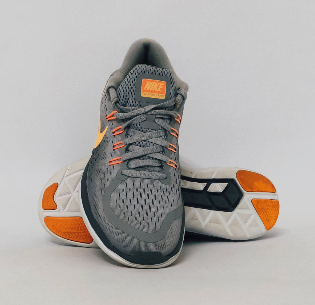 grey Nike Flex 2017 RN running shoe featuring an orange Swoosh and a flexible white midsole.