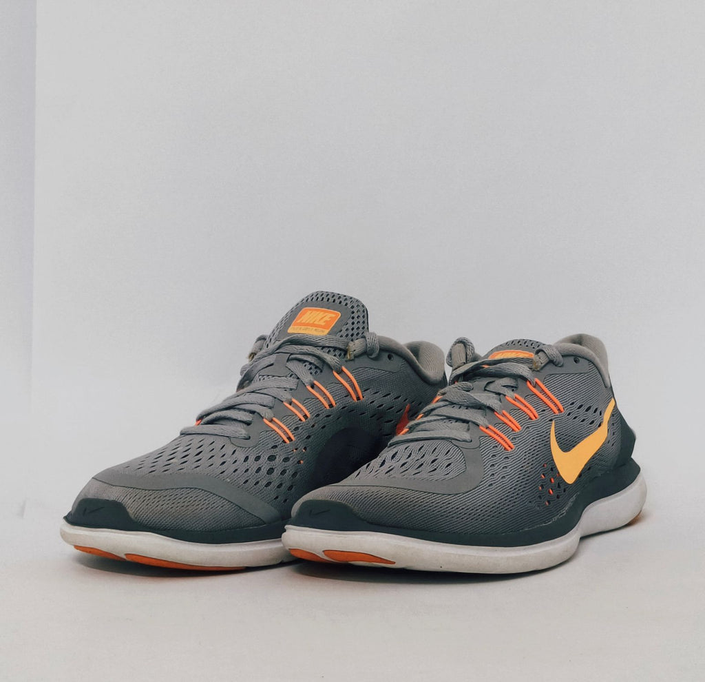 grey Nike Flex 2017 RN running shoe featuring an orange Swoosh and a flexible white midsole.