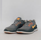 grey Nike Flex 2017 RN running shoe featuring an orange Swoosh and a flexible white midsole.