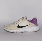 cream-colored Nike Flex Experience running shoe featuring a purple ankle collar, a black Swoosh, and a white flexible midsole.