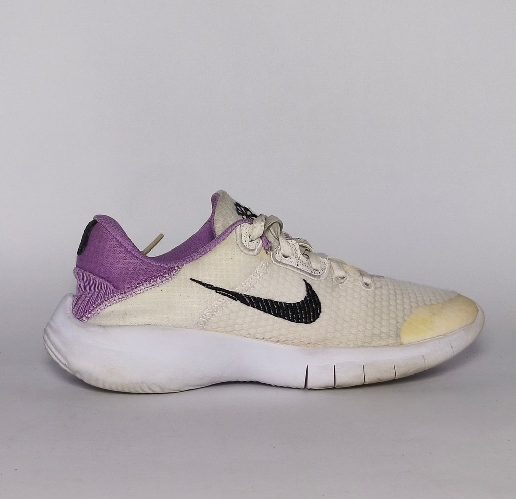 cream-colored Nike Flex Experience running shoe featuring a purple ankle collar, a black Swoosh, and a white flexible midsole.