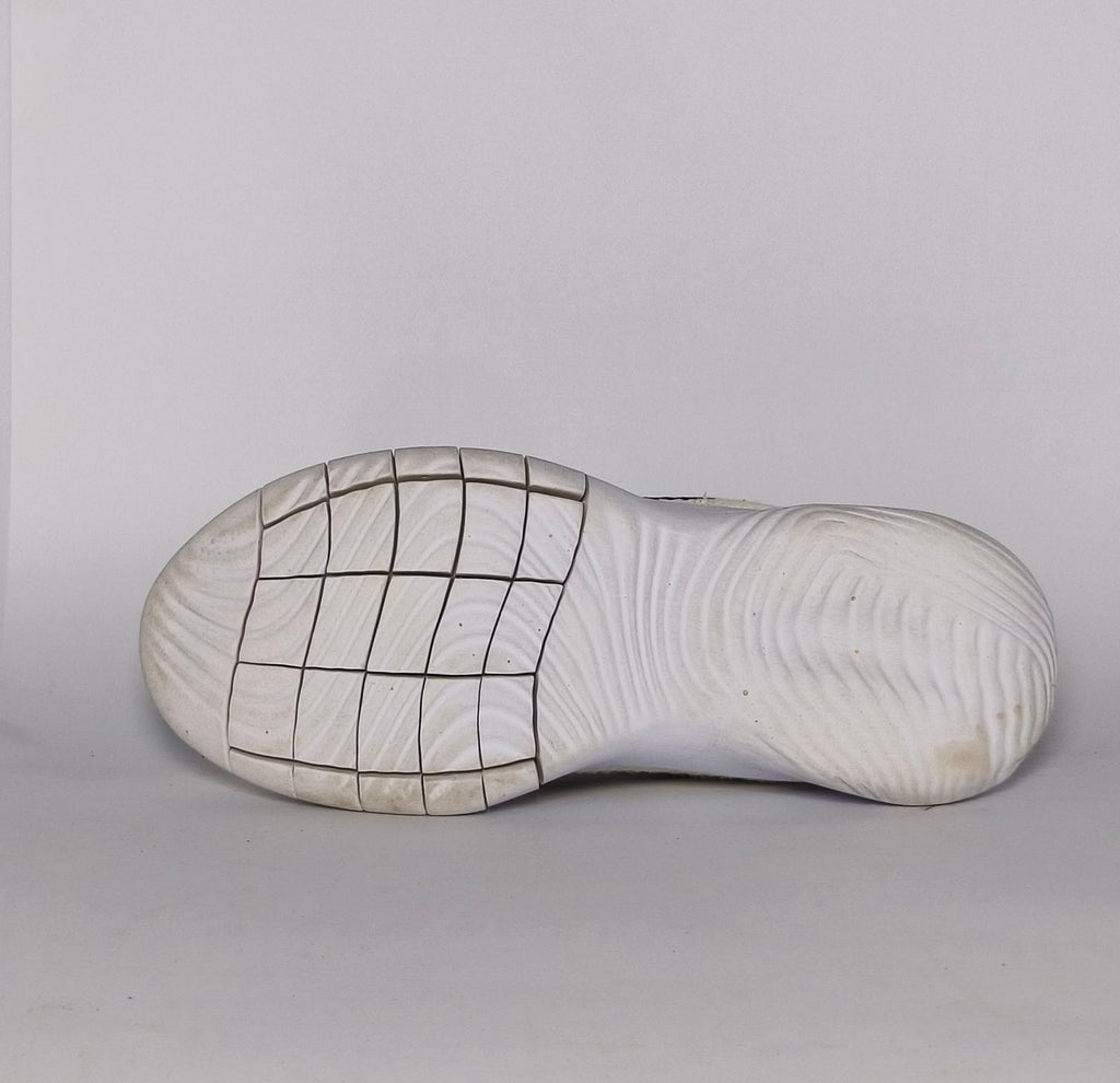 cream-colored Nike Flex Experience running shoe featuring a purple ankle collar, a black Swoosh, and a white flexible midsole.