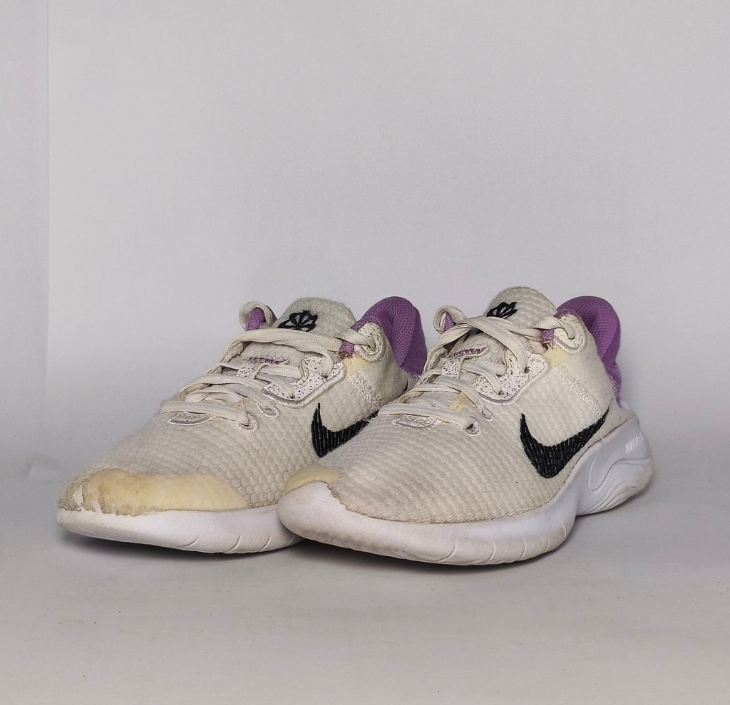 cream-colored Nike Flex Experience running shoe featuring a purple ankle collar, a black Swoosh, and a white flexible midsole.
