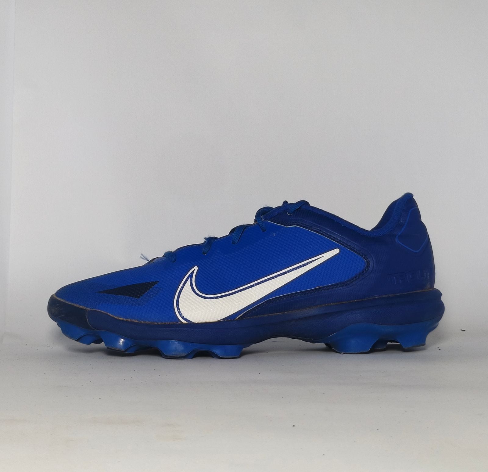 royal blue Nike Alpha Huarache baseball cleat featuring a white Swoosh and a specialized molded cleat outsole for field traction.