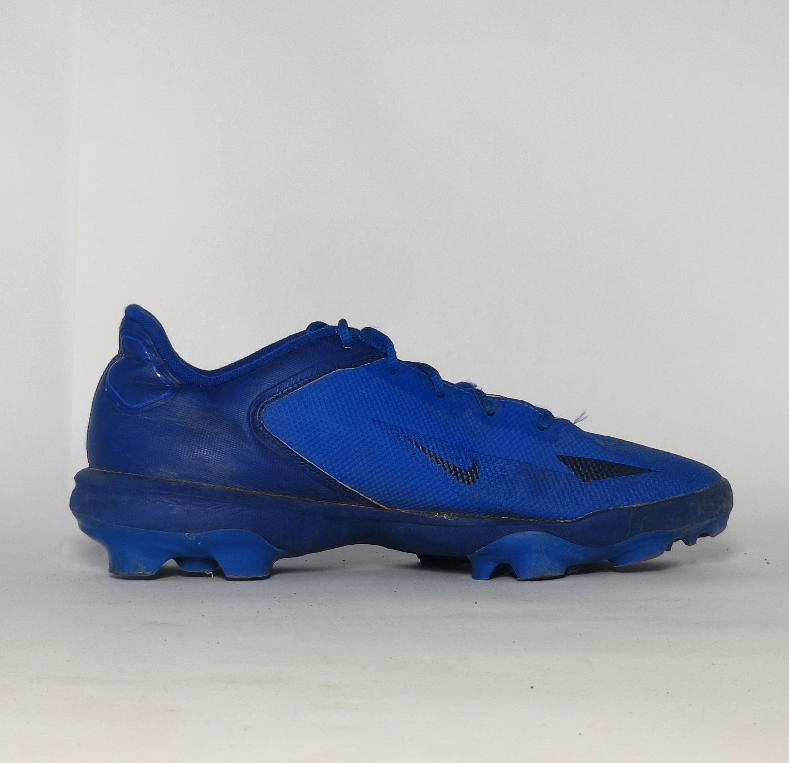royal blue Nike Alpha Huarache baseball cleat featuring a white Swoosh and a specialized molded cleat outsole for field traction.