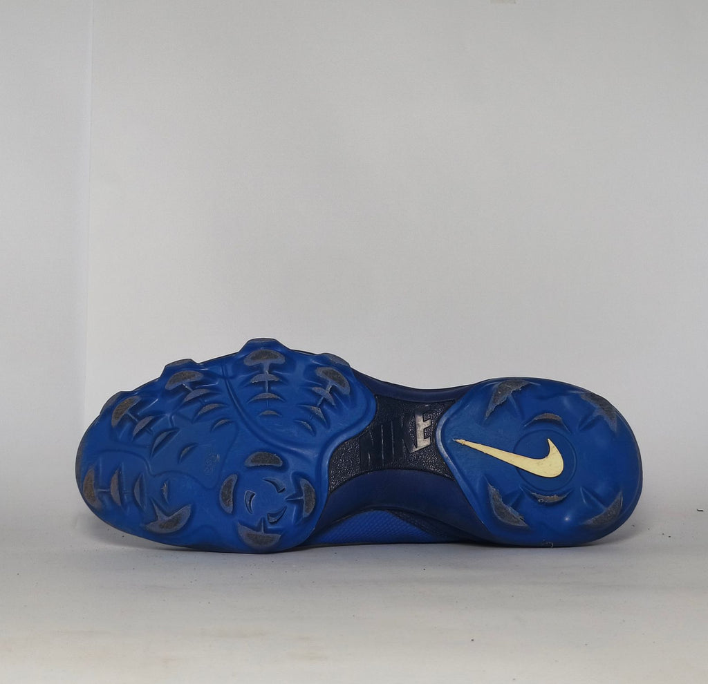 royal blue Nike Alpha Huarache baseball cleat featuring a white Swoosh and a specialized molded cleat outsole for field traction.