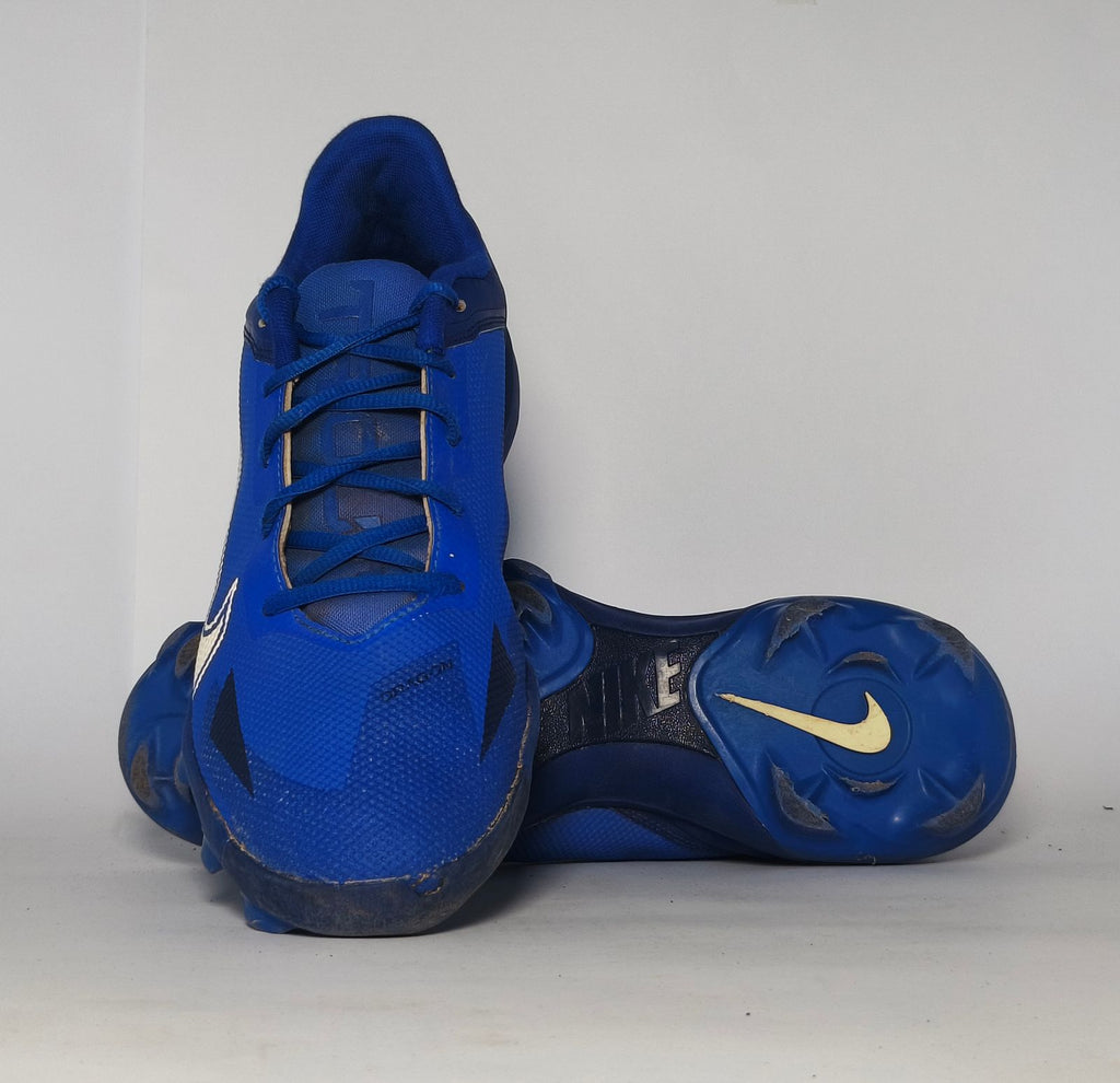 royal blue Nike Alpha Huarache baseball cleat featuring a white Swoosh and a specialized molded cleat outsole for field traction.