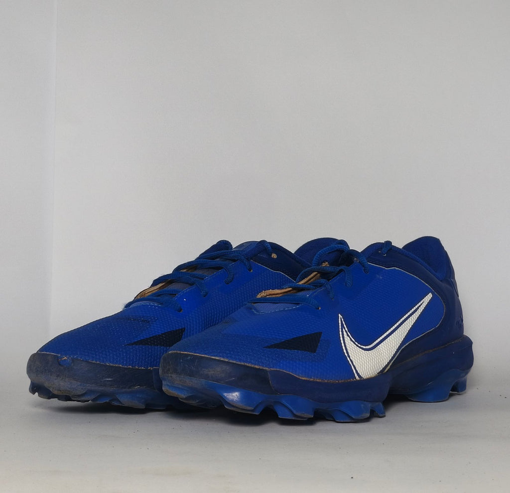 royal blue Nike Alpha Huarache baseball cleat featuring a white Swoosh and a specialized molded cleat outsole for field traction.