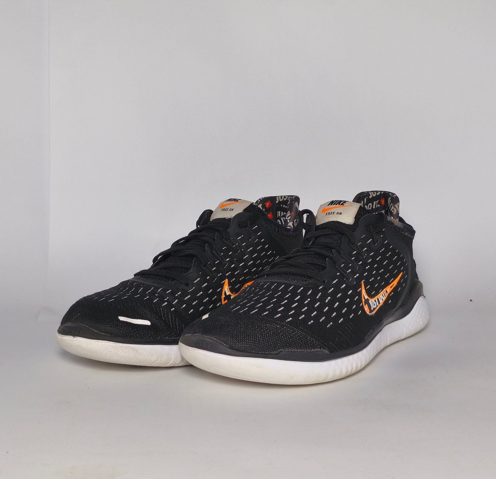 Nike Free RN 2018 running shoe featuring an orange "Just Do It" Swoosh and a white flexible midsole.