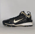 black Nike Huarache baseball cleat featuring a white Swoosh, gold heel accents, and a white midsole with a cleated outsole.