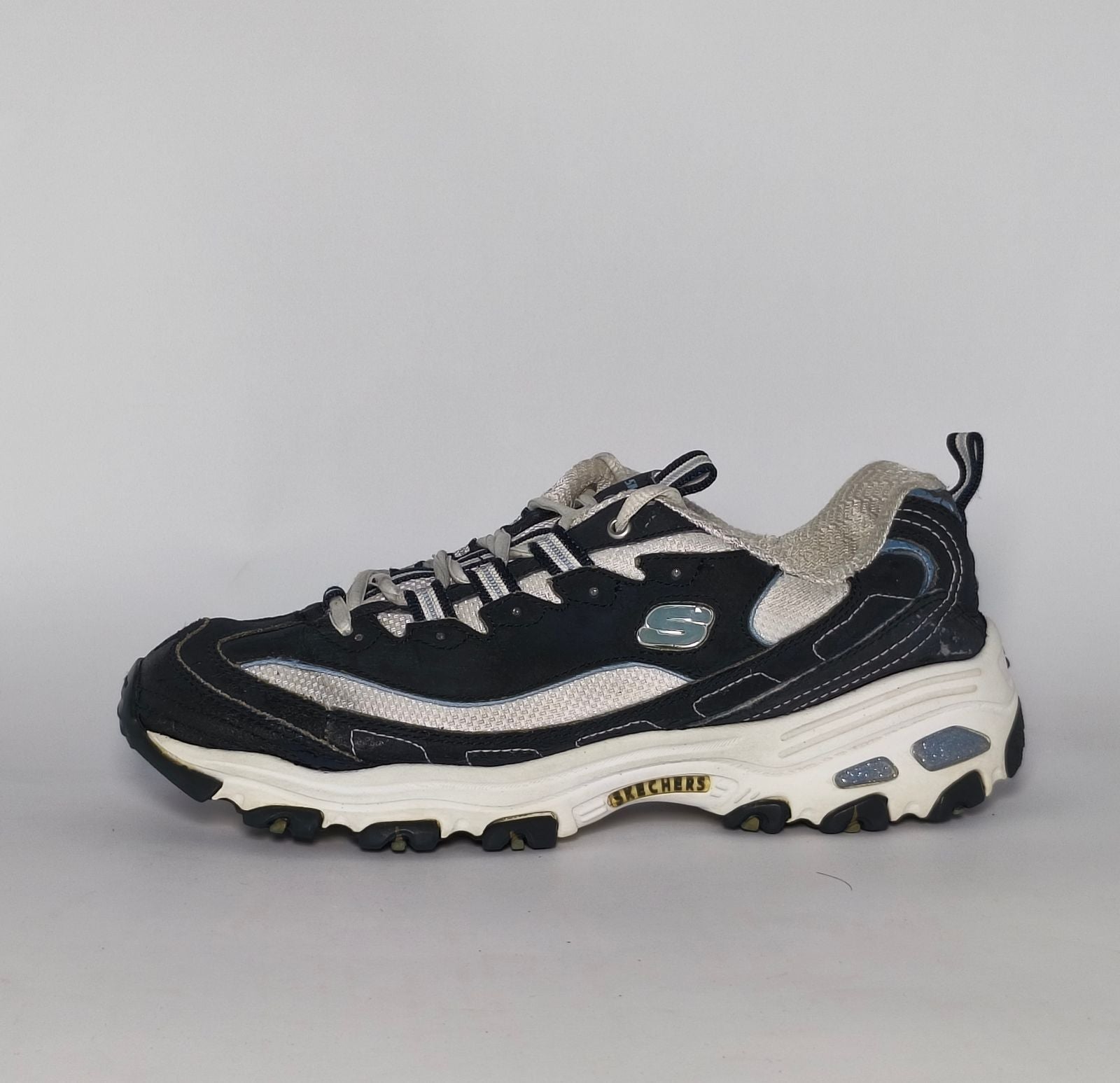 navy blue and silver Skechers D'Lites sneaker featuring a thick white midsole and a rugged black traction outsole.