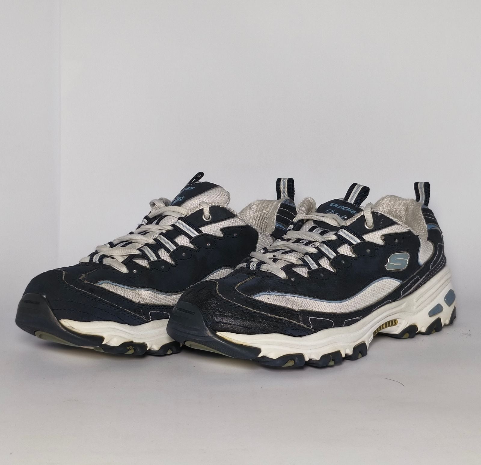 navy blue and silver Skechers D'Lites sneaker featuring a thick white midsole and a rugged black traction outsole.