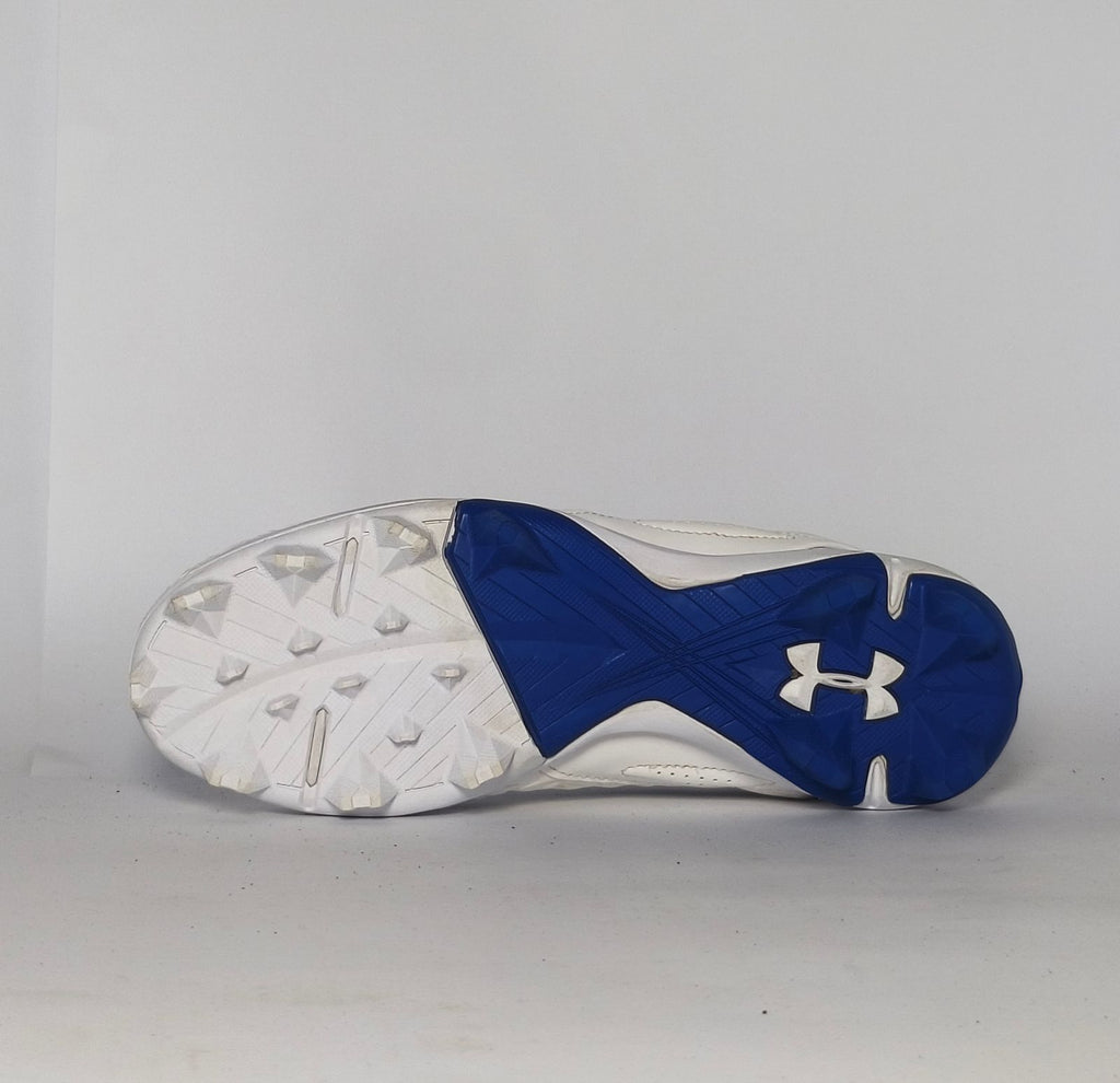 white and royal blue Under Armour cleat featuring a textured forefoot and a durable molded cleat outsole.