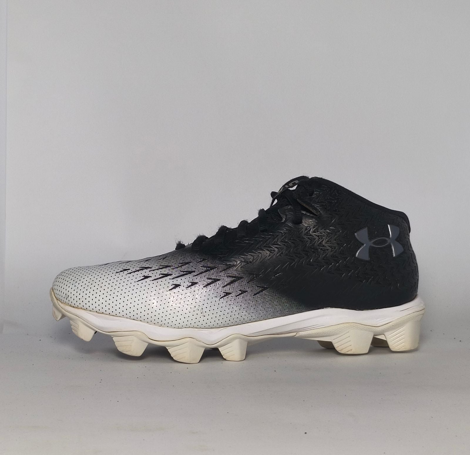 black and silver gradient Under Armour football cleat featuring a textured upper and a white molded cleat outsole.