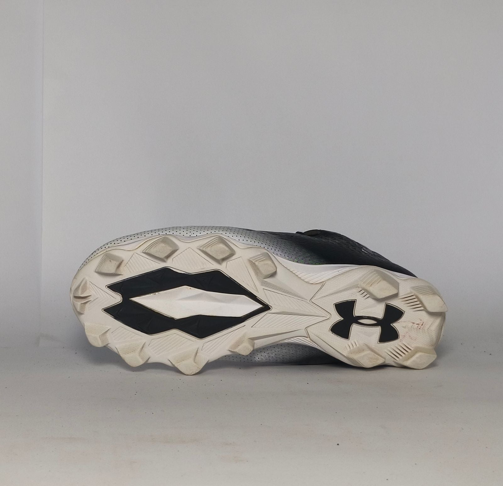 black and silver gradient Under Armour football cleat featuring a textured upper and a white molded cleat outsole.
