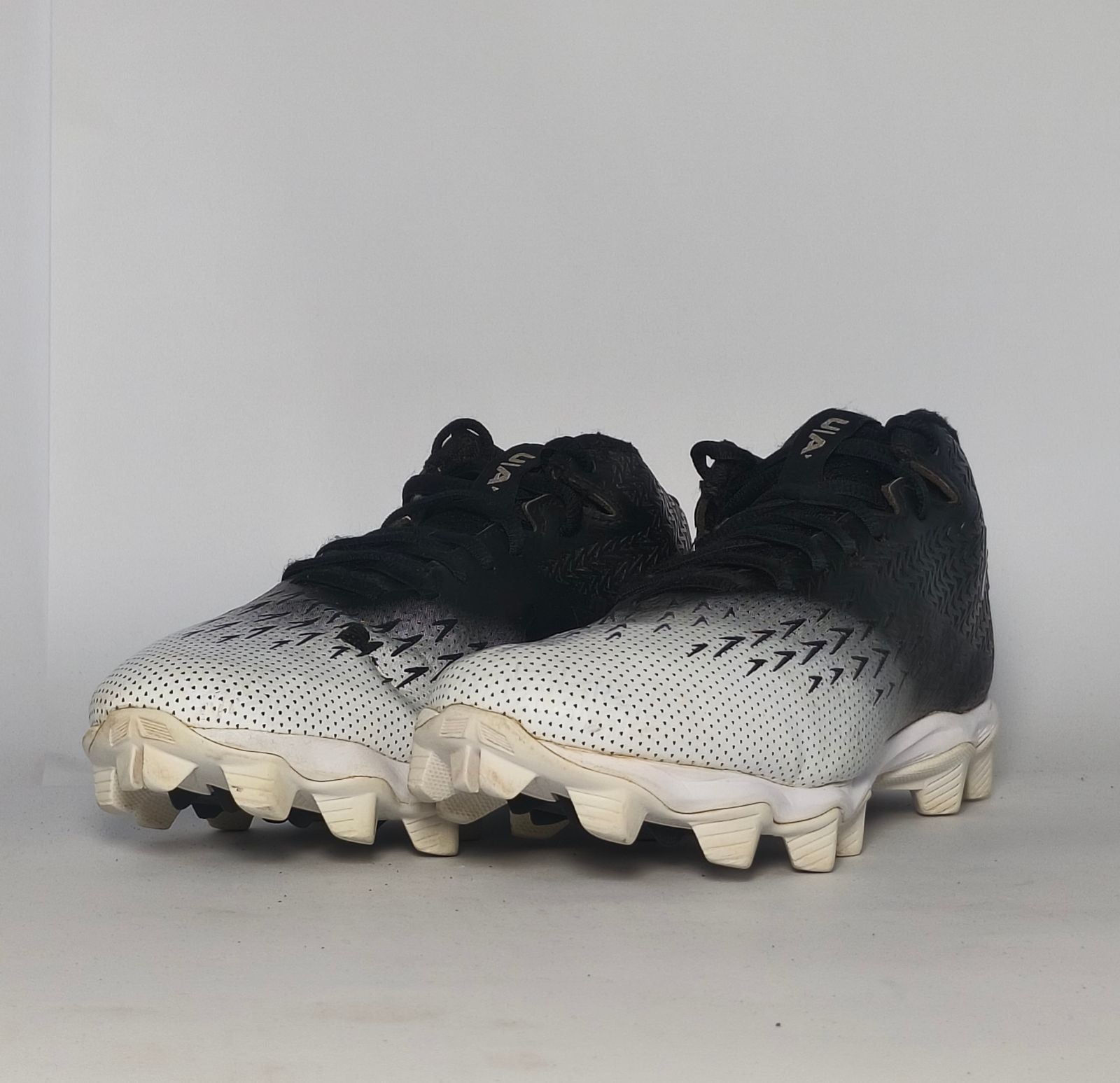 black and silver gradient Under Armour football cleat featuring a textured upper and a white molded cleat outsole.