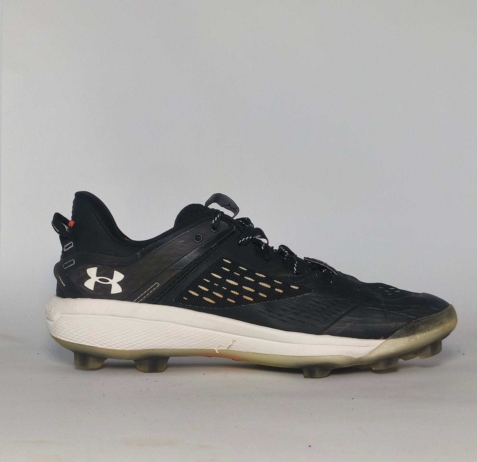 black Under Armour Harper baseball cleat featuring a white logo, white midsole, and a specialized cleated outsole for field traction.