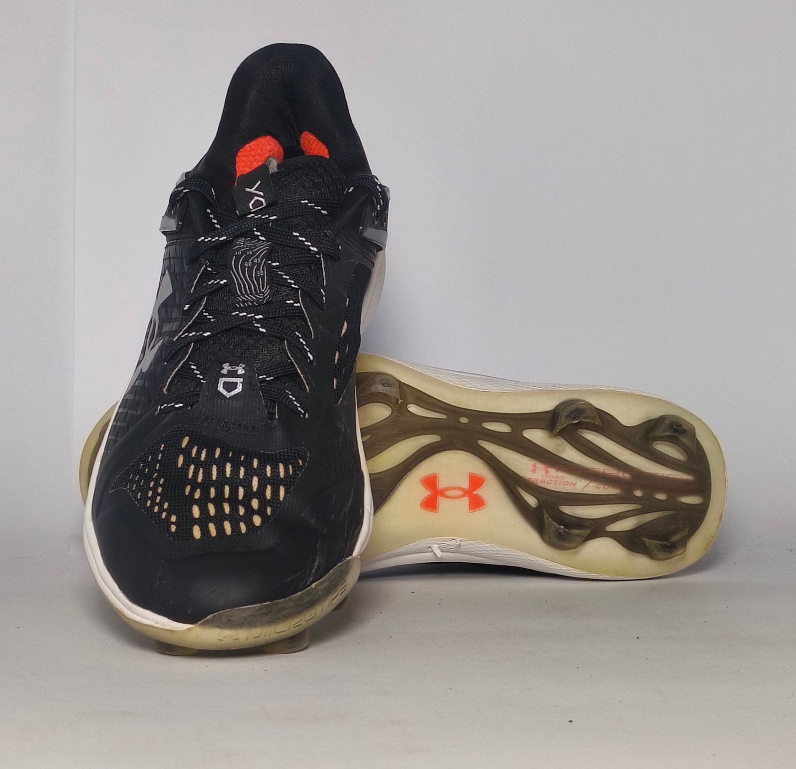 black Under Armour Harper baseball cleat featuring a white logo, white midsole, and a specialized cleated outsole for field traction.