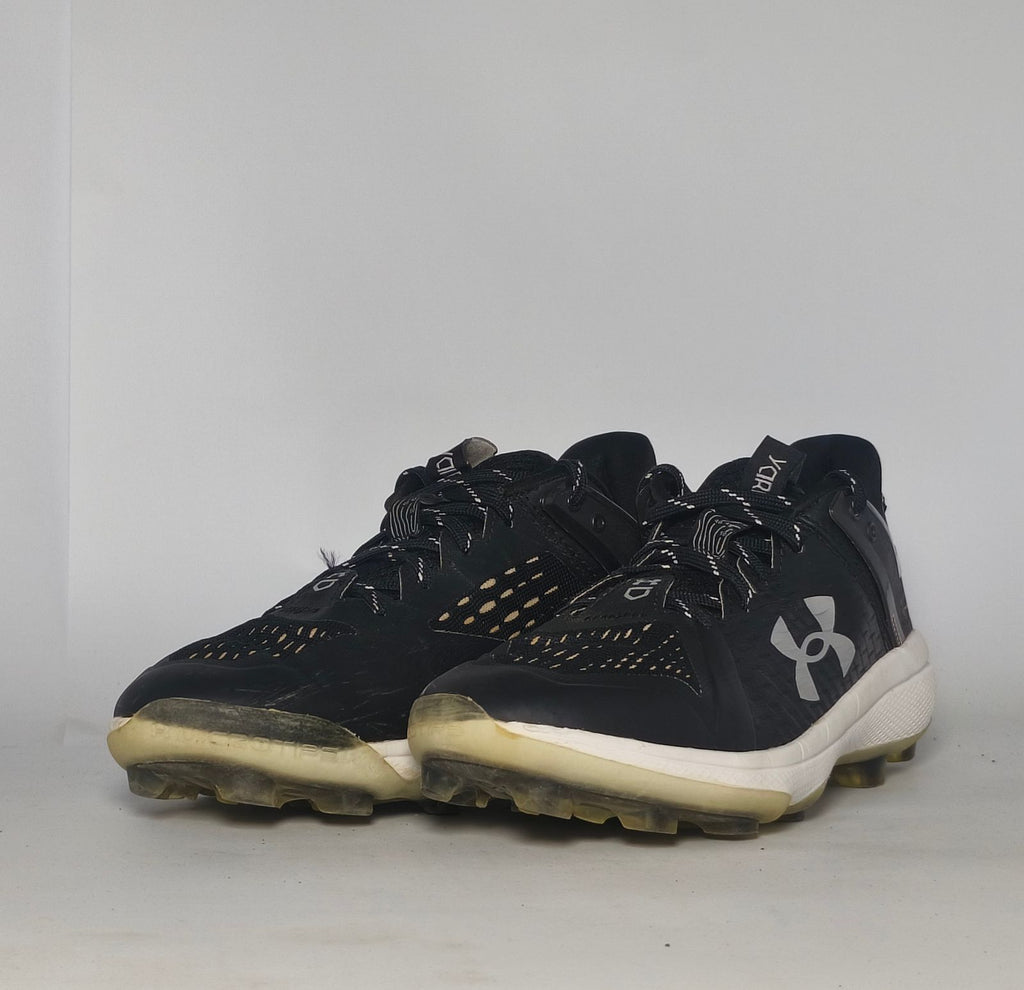 black Under Armour Harper baseball cleat featuring a white logo, white midsole, and a specialized cleated outsole for field traction.